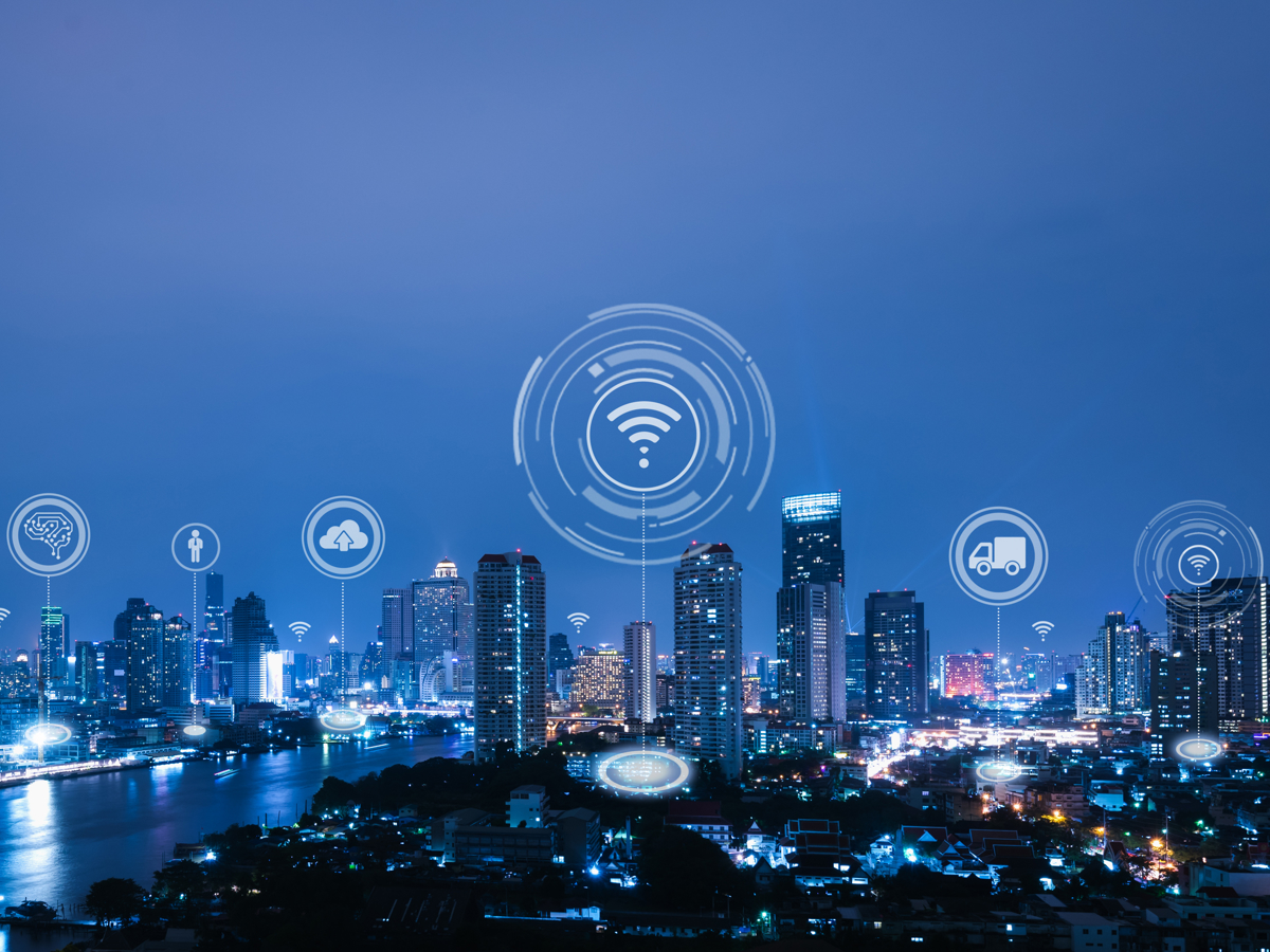 The benefits of IoT in smart cities are illustrated with a cityscape at night.