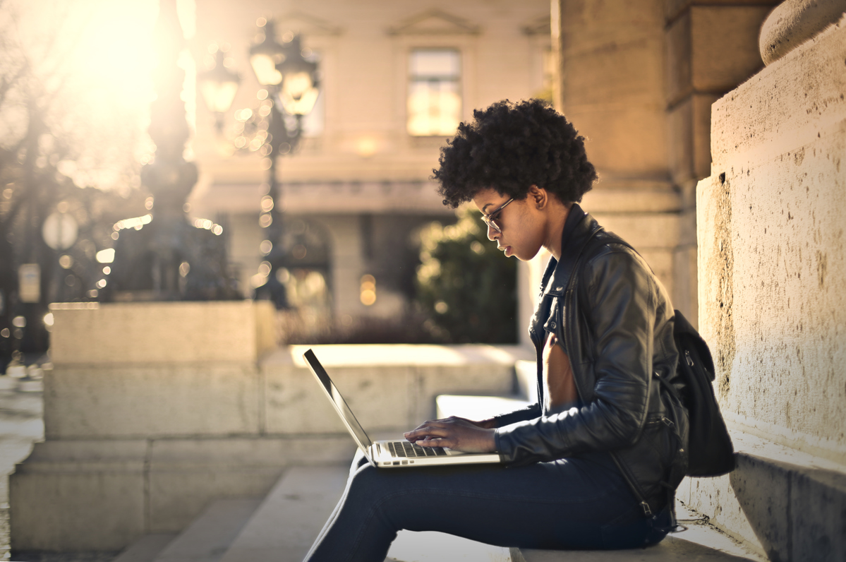 A person uses a laptop outdoors, which is why top access point brands need a wide range.